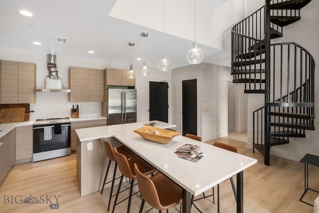 kitchen featuring appliances with stainless steel finishes, light brown cabinetry, light hardwood / wood-style floors, a kitchen island, and range hood