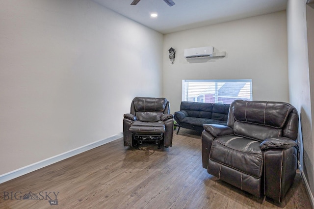 sitting room with wood-type flooring, an AC wall unit, and ceiling fan