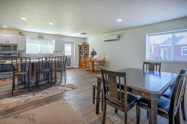 dining space with dark wood-type flooring, a wall mounted air conditioner, and a textured ceiling