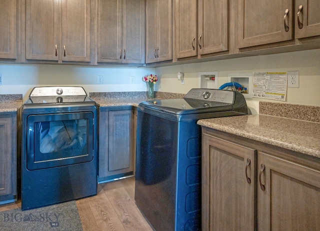 laundry room featuring light hardwood / wood-style flooring, cabinets, and washing machine and clothes dryer