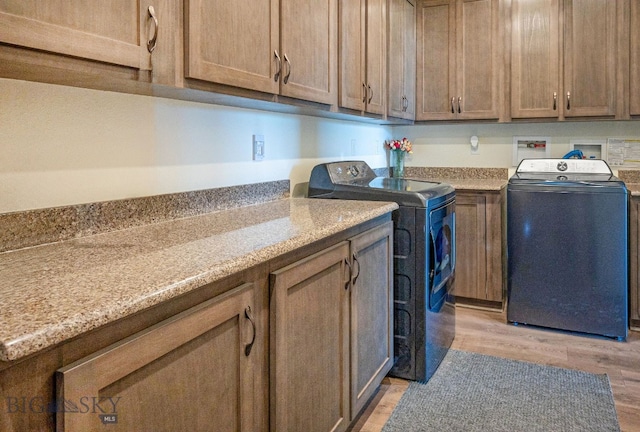 laundry room featuring cabinets, washer and clothes dryer, and light wood-type flooring