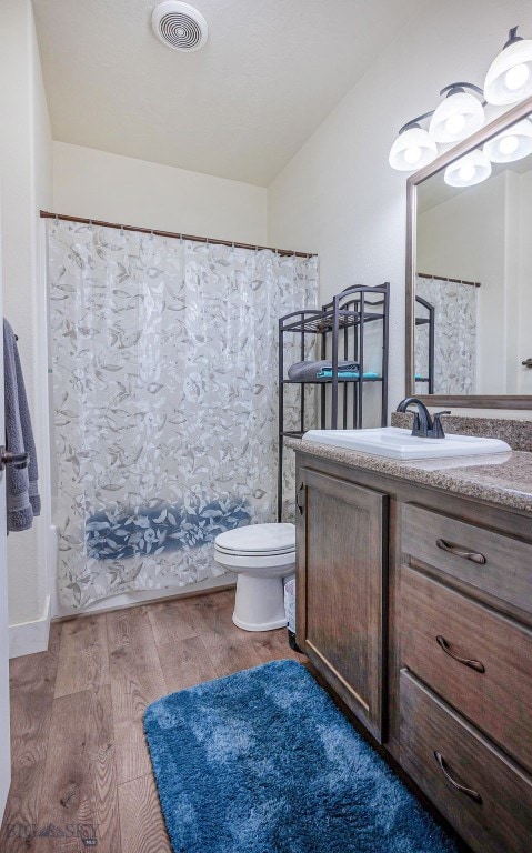 full bathroom featuring vanity, hardwood / wood-style floors, shower / tub combo with curtain, and toilet