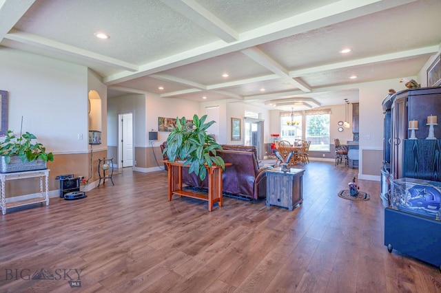 living room with beamed ceiling, wood-type flooring, coffered ceiling, a notable chandelier, and a textured ceiling