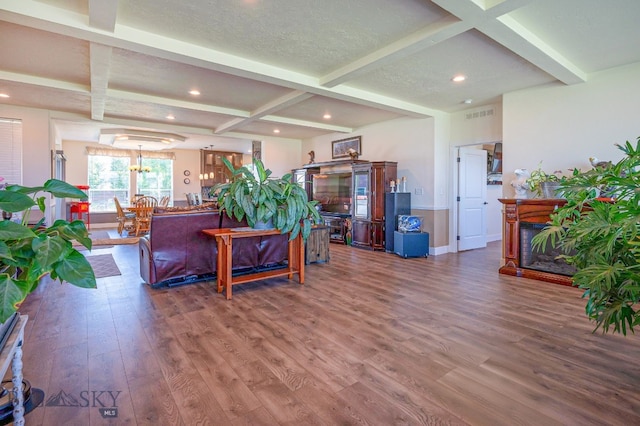 living room featuring coffered ceiling, hardwood / wood-style floors, beamed ceiling, and a multi sided fireplace