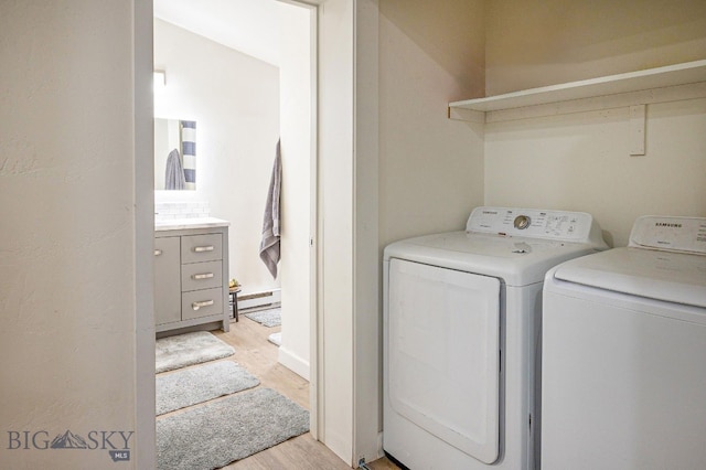 laundry room with a baseboard heating unit, washer and clothes dryer, and light hardwood / wood-style flooring