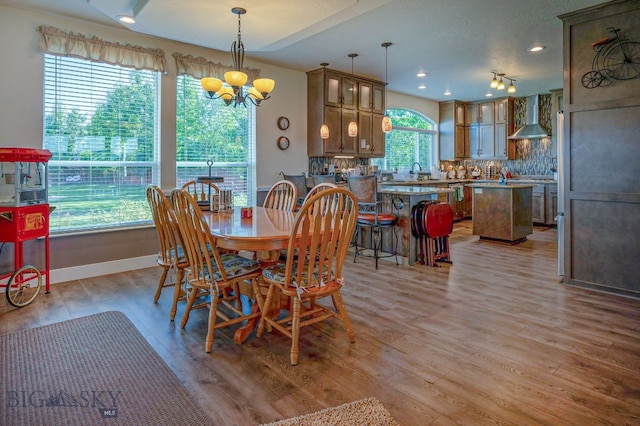 dining area with sink, light hardwood / wood-style flooring, and a notable chandelier