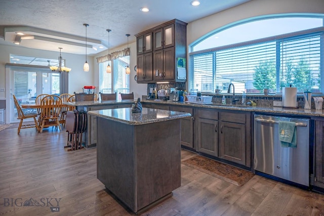 kitchen with sink, dark brown cabinets, stainless steel dishwasher, pendant lighting, and dark stone counters