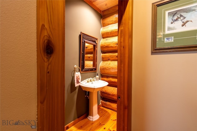 bathroom with wood-type flooring and log walls