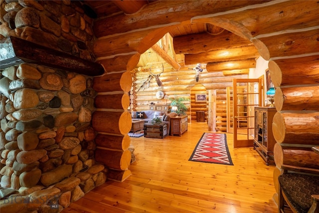 living room with beam ceiling, light hardwood / wood-style floors, french doors, and log walls