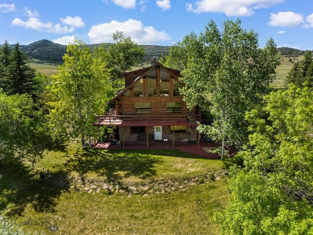 back of property featuring a lawn and a deck with mountain view