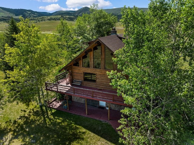 exterior space featuring a deck with mountain view, a patio area, and a lawn