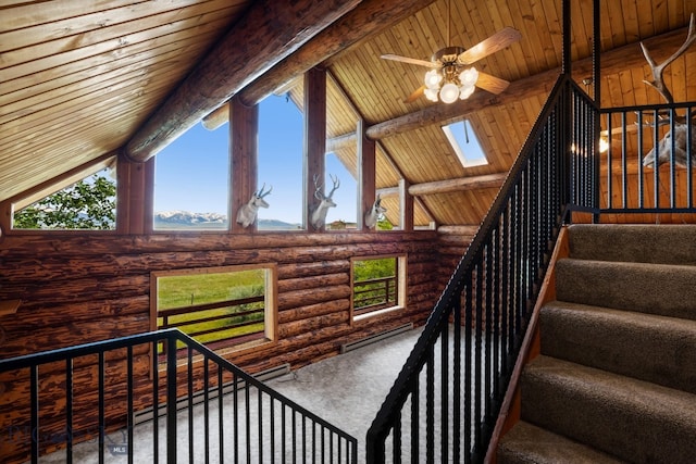 staircase with beam ceiling, a skylight, rustic walls, wood ceiling, and ceiling fan