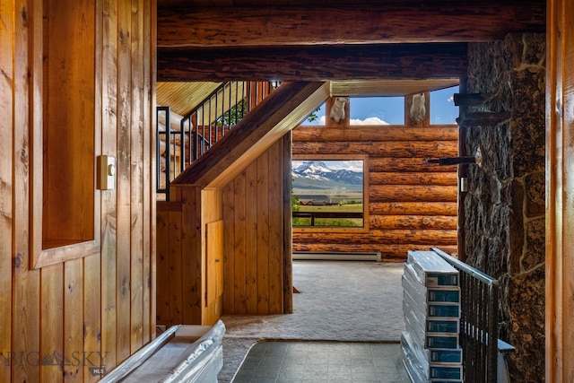 interior space with carpet, beam ceiling, a baseboard heating unit, and log walls