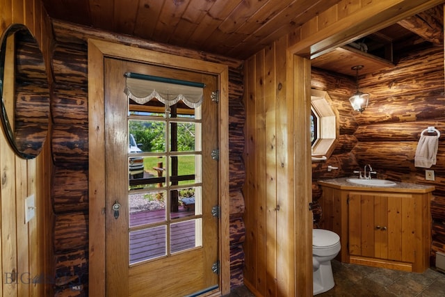 bathroom with wood ceiling, rustic walls, tile patterned floors, toilet, and vanity