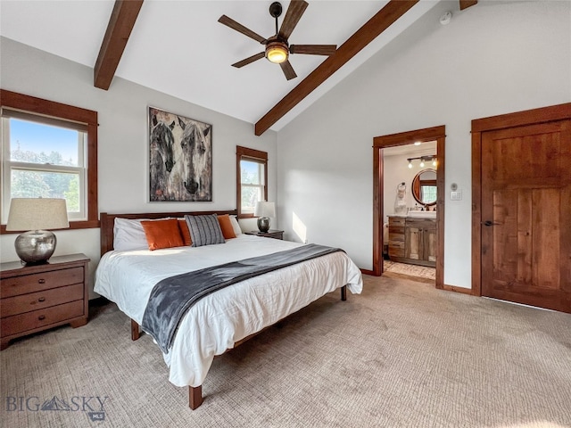 carpeted bedroom with multiple windows, ensuite bath, ceiling fan, and vaulted ceiling with beams