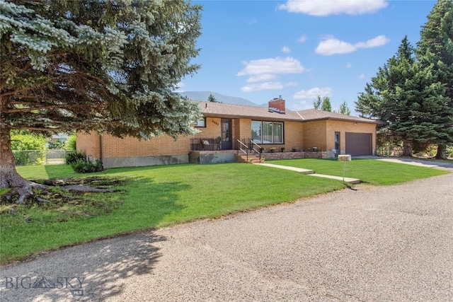 single story home with a garage, concrete driveway, a chimney, a front lawn, and brick siding