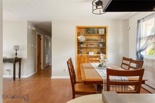 dining space featuring baseboard heating, baseboards, and wood finished floors