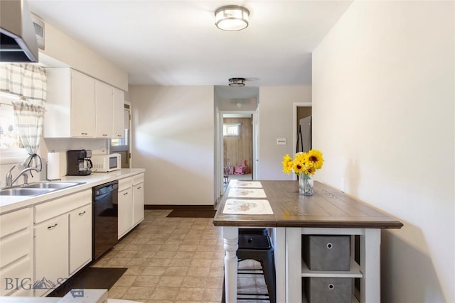 kitchen with black dishwasher, light countertops, white microwave, and white cabinetry