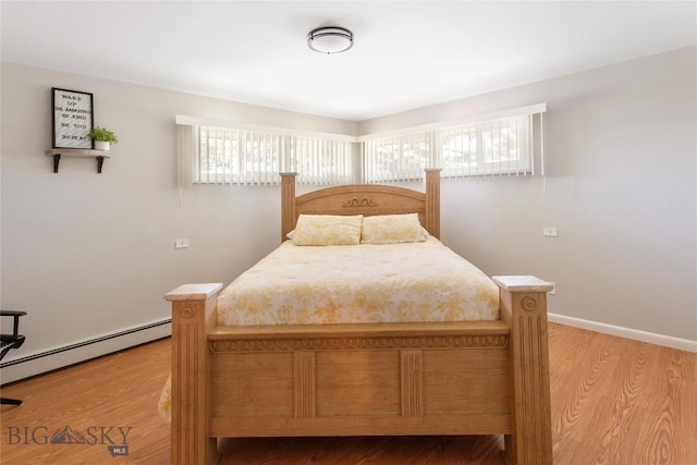 bedroom featuring multiple windows, a baseboard radiator, wood finished floors, and baseboards