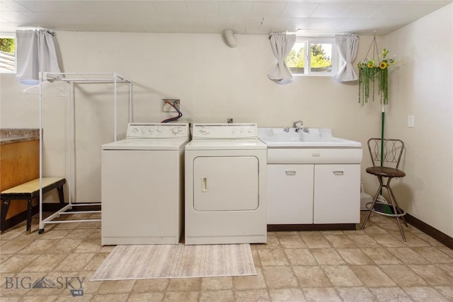 washroom featuring baseboards, cabinet space, stone finish flooring, and washing machine and clothes dryer