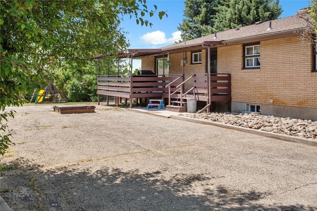 rear view of house featuring a deck and brick siding