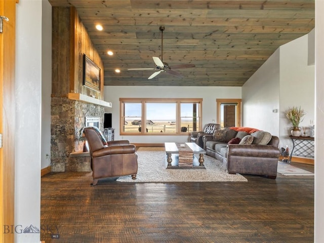 living room featuring ceiling fan, wood ceiling, a stone fireplace, and dark wood-type flooring