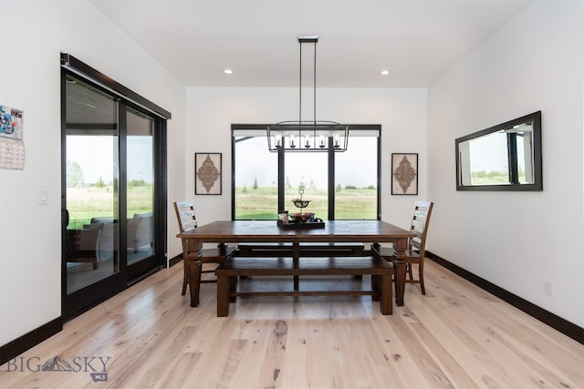 dining space with a healthy amount of sunlight, a notable chandelier, and light hardwood / wood-style flooring