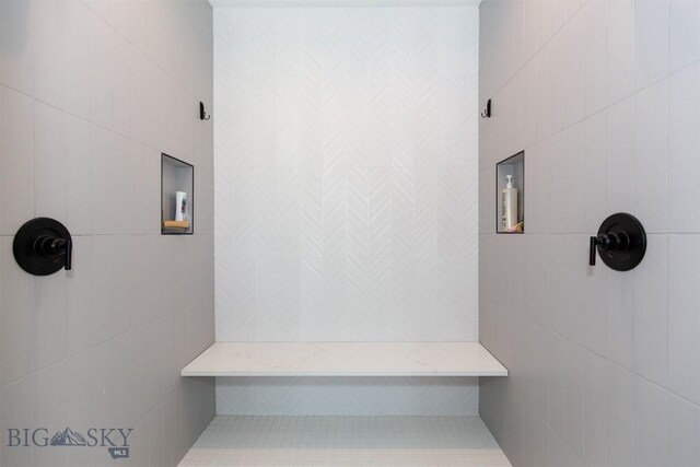 bathroom with tiled shower and tile walls