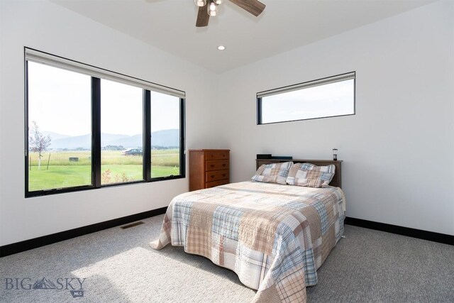 carpeted bedroom with ceiling fan and a mountain view