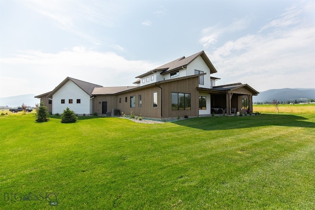 back of house featuring cooling unit, a yard, and a mountain view