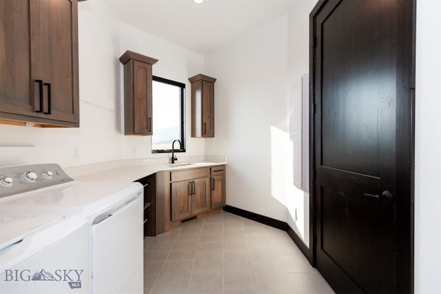 clothes washing area featuring sink, washing machine and dryer, cabinets, and light tile patterned floors