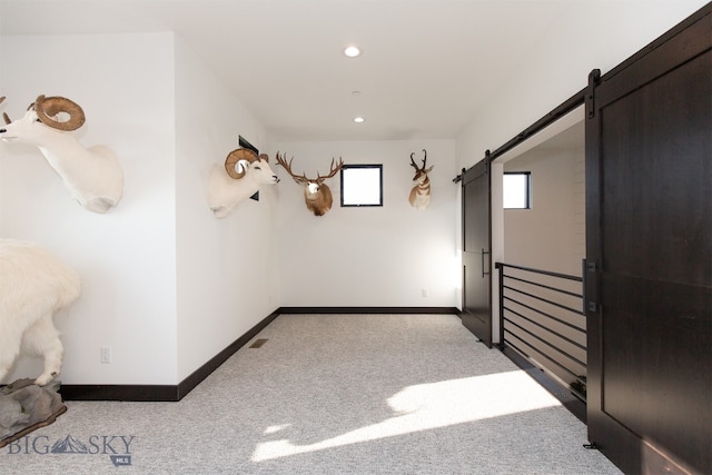 unfurnished room with light carpet and a barn door