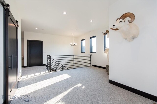 interior space featuring a notable chandelier, a barn door, and carpet floors