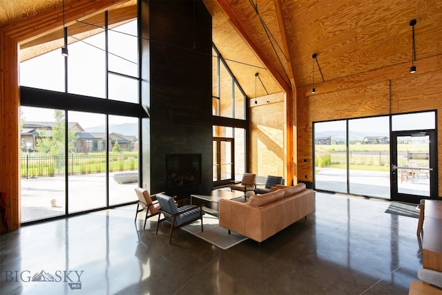 living room with concrete floors, a fireplace, expansive windows, and high vaulted ceiling