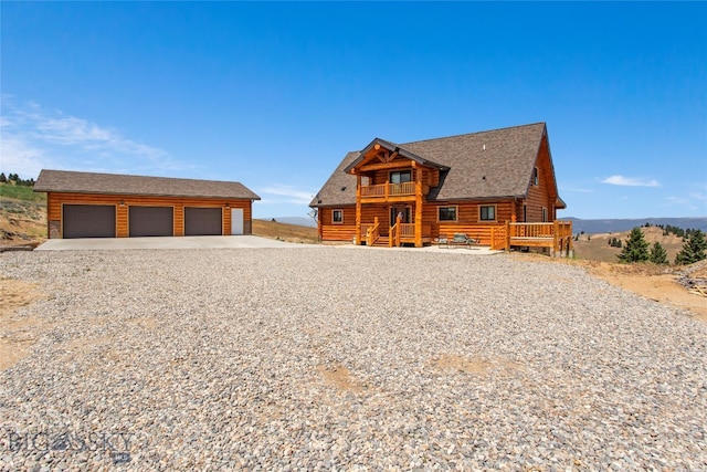 cabin featuring a wooden deck, a garage, and an outbuilding