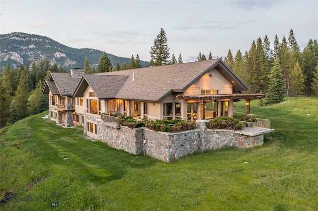 back of property featuring a lawn and a mountain view