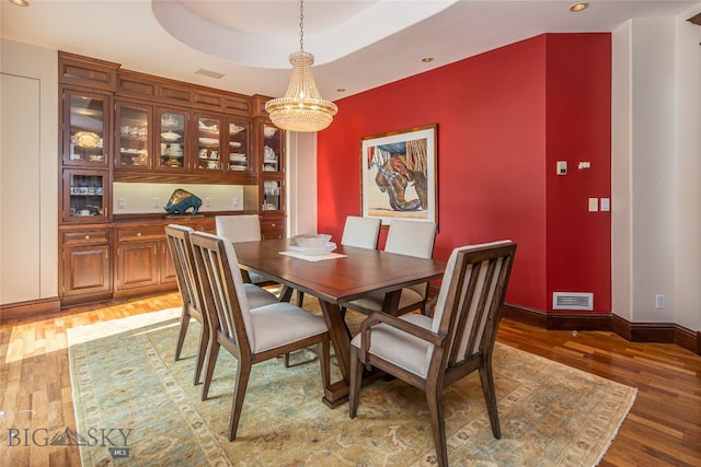 dining space featuring dark hardwood / wood-style flooring, a tray ceiling, and an inviting chandelier