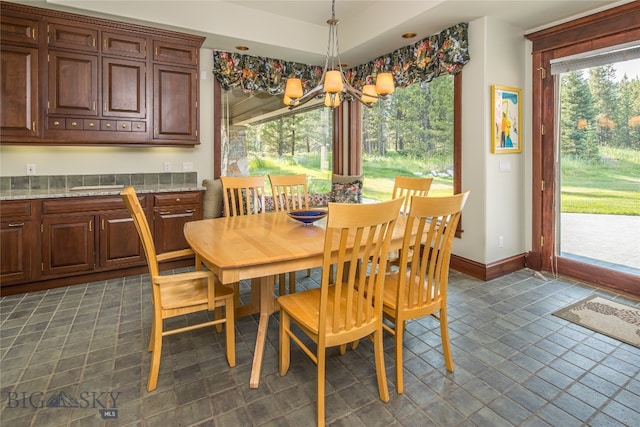 dining space with dark tile patterned flooring and a notable chandelier