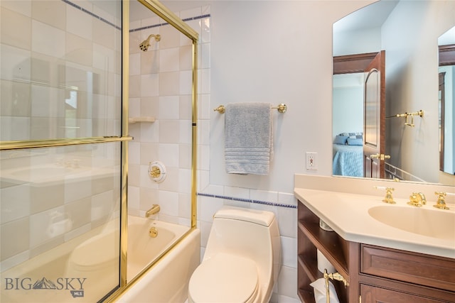 full bathroom featuring tile walls, vanity, combined bath / shower with glass door, and toilet