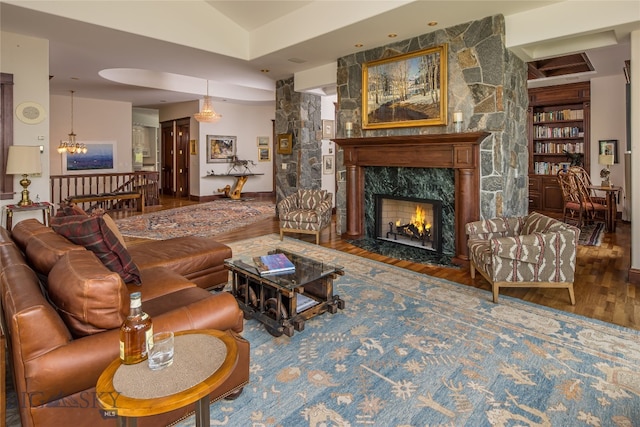 living room featuring built in shelves, a chandelier, wood-type flooring, and a large fireplace