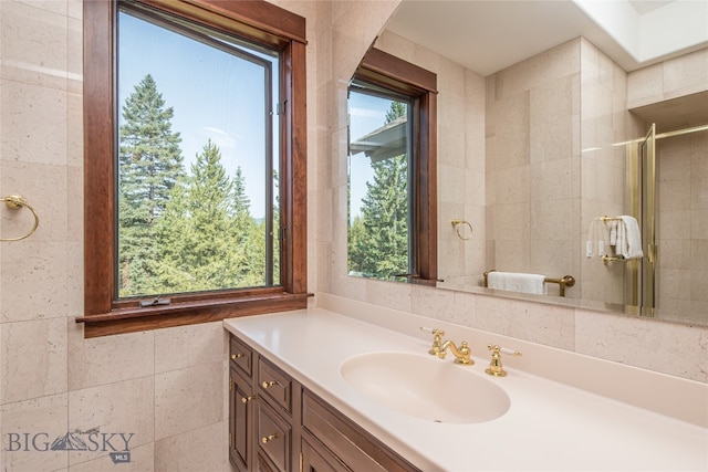 bathroom with tile walls, vanity, and a shower with door