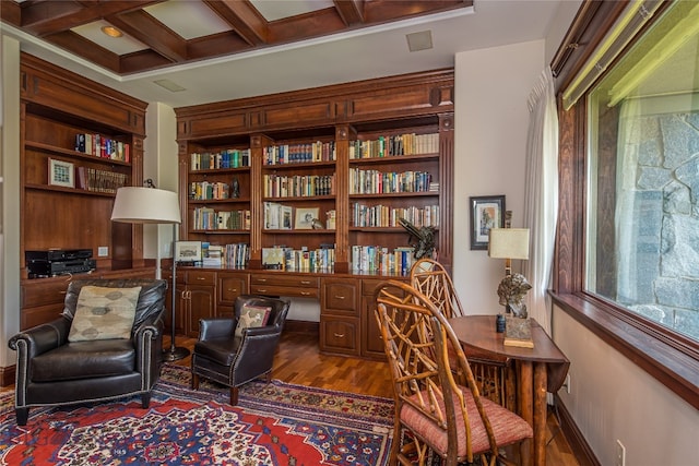 sitting room featuring dark wood-type flooring, coffered ceiling, built in desk, and beamed ceiling