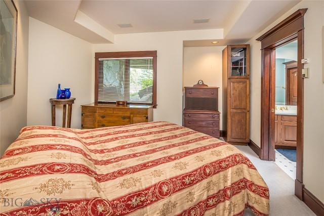 bedroom featuring ensuite bath, sink, and light colored carpet