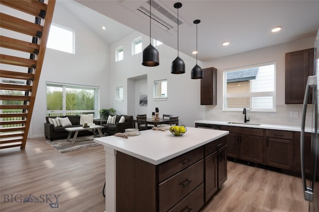 kitchen featuring sink, decorative backsplash, light wood-type flooring, and hanging light fixtures