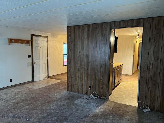 unfurnished room featuring light tile patterned flooring and wooden walls