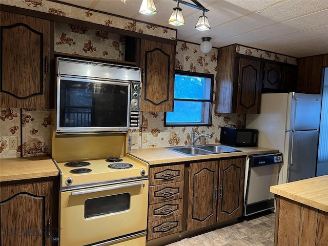 kitchen with white range with electric cooktop, sink, dishwashing machine, light tile patterned floors, and refrigerator