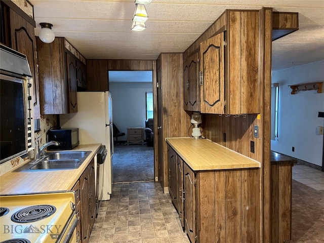 kitchen featuring wood walls, electric range oven, tile patterned floors, and sink