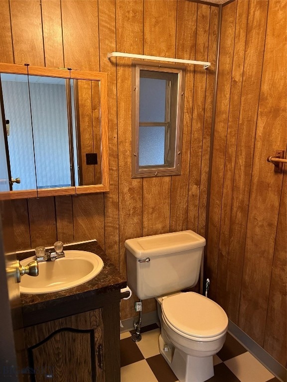 bathroom featuring vanity, toilet, tile patterned flooring, and wooden walls