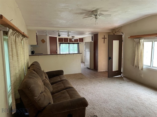 unfurnished living room featuring a textured ceiling, light carpet, a healthy amount of sunlight, and ceiling fan