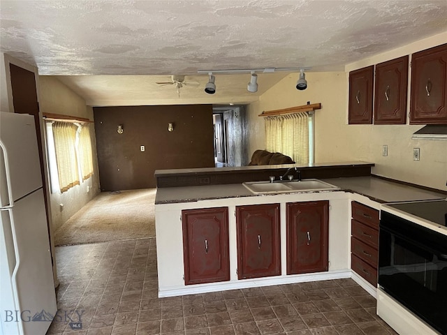 kitchen with white appliances, kitchen peninsula, dark tile patterned flooring, vaulted ceiling, and sink